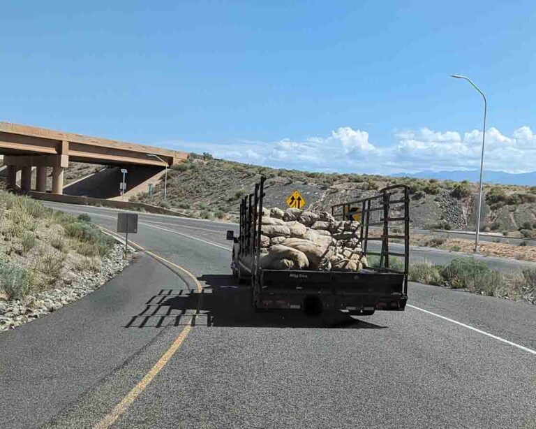 A trailer full of Hatch chile sacks pulling off of I-25 onto the offramp to Cerillos road in Santa Fe