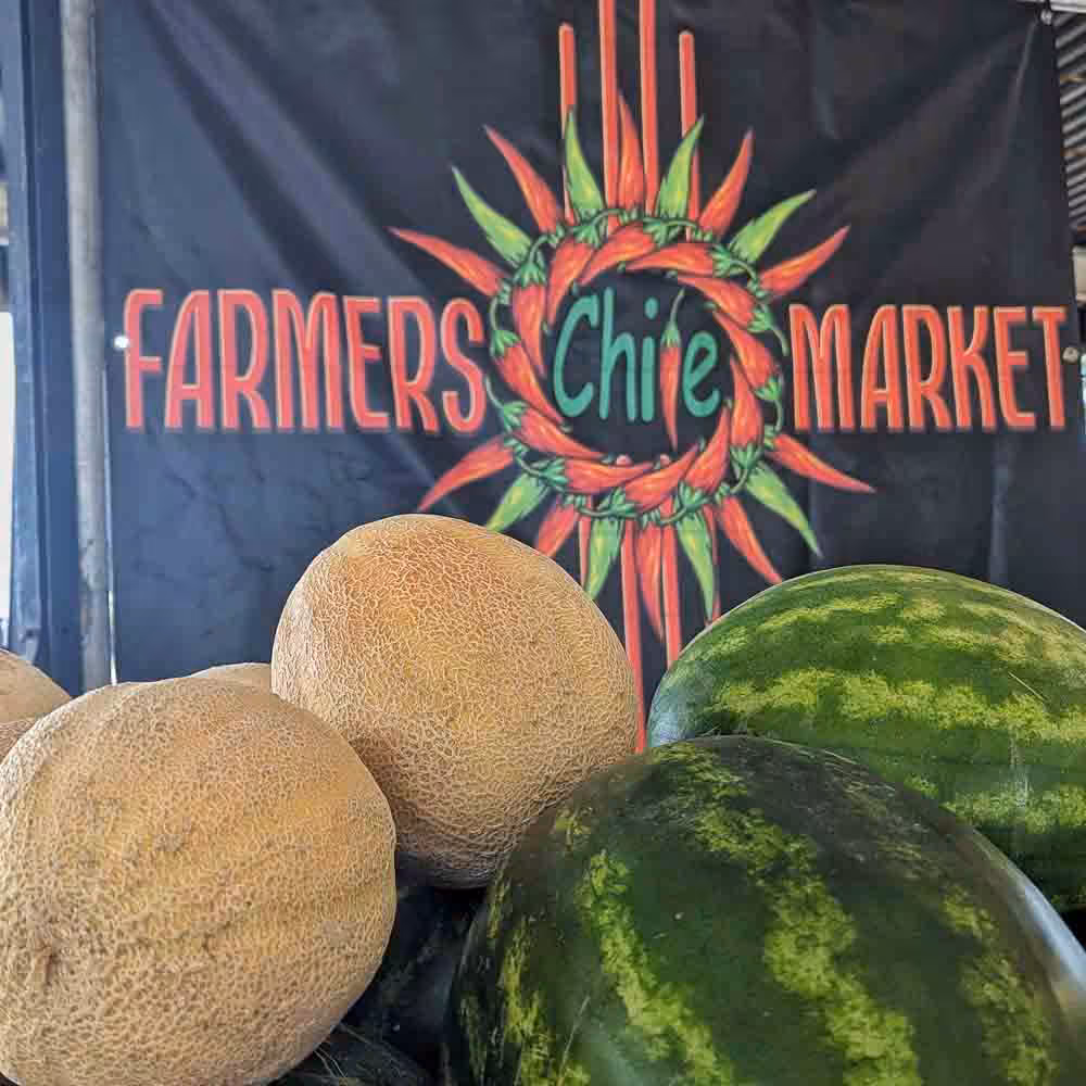 locally grown cantaloupes and watermelons in front of Farmers Chile Market sign in Albuquerque, New Mexico