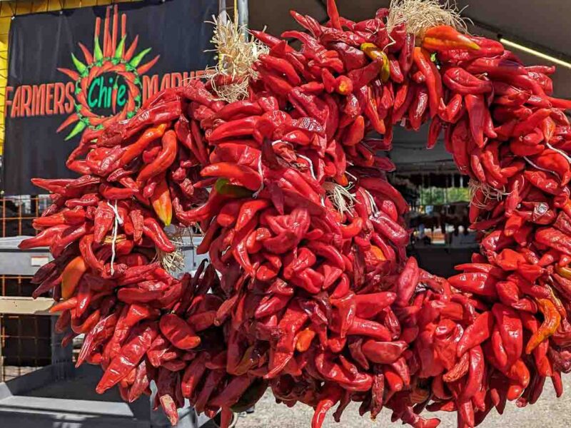 red chile wreaths and farmers chile market logo two Hatch red chile wreaths in front of Farmers Chile Market in Albuquerque, NM