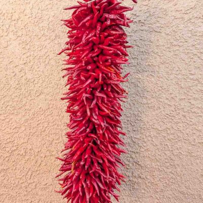 a 2 ft hatch pequin chile ristra in front of New Mexican adobe building