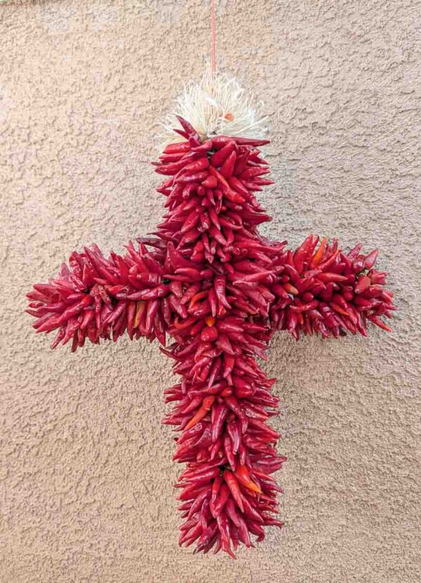 a special shapre Hatch pequin chile ristra cross in front of a New Mexican stucco building