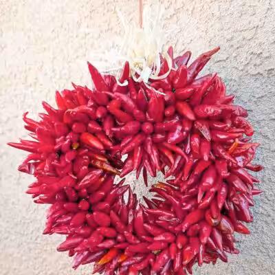 a small Hatch pequin chile ristra wreath in front of New Mexican stucco building
