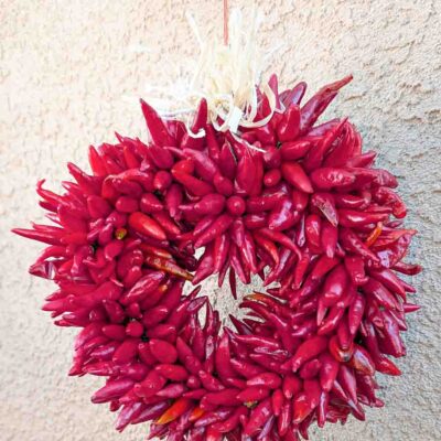 a small Hatch pequin chile ristra wreath in front of New Mexican stucco building