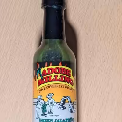 a bottle of adobe milling green jalapeno hot sauce