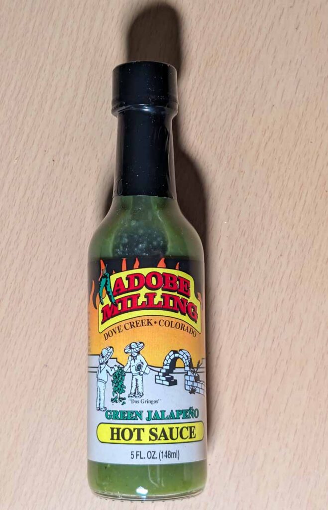 a bottle of adobe milling green jalapeno hot sauce